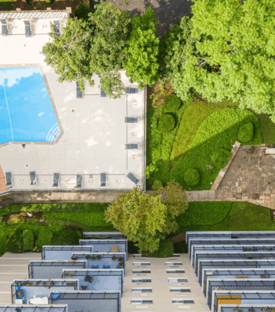 Aerial view of a residential area with pool, greenery, and apartment buildings.